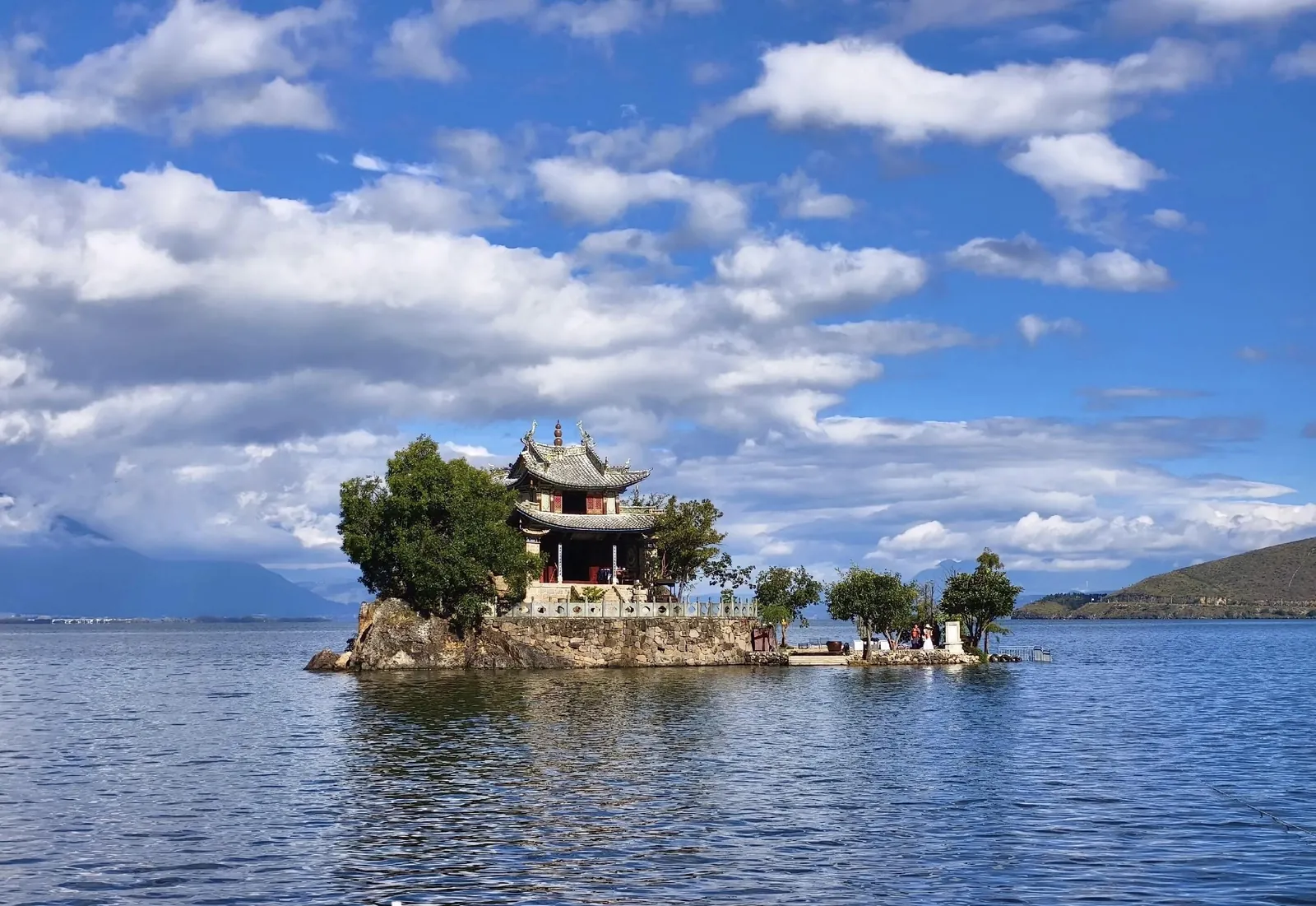 The tiny temple islet of Xiaoputuo on Erhai Lake beneath towering white clouds