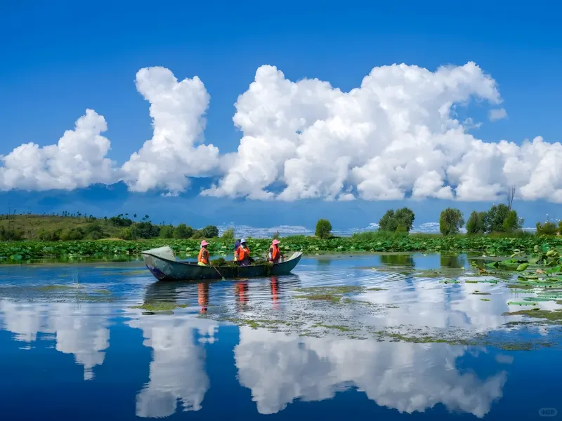 A small wooden boat on Erhai Lake in Dali beneath towering summer clouds