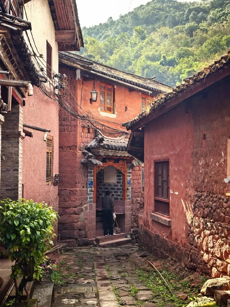 A red-earth lane between old houses in Nuodeng