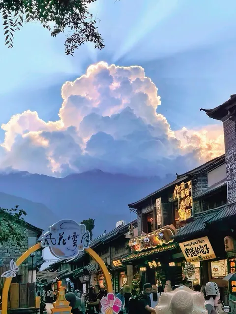 Dali Old Town street beneath sunlit clouds and the Cangshan range