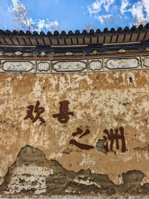 A weathered Bai wall in Xizhou beneath carved eaves